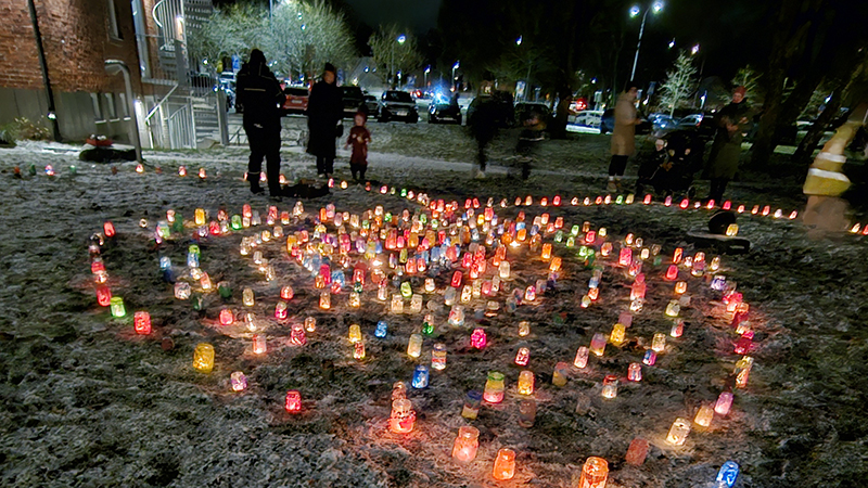 Färgglada ljuslyktor står på mark täckt av snö.